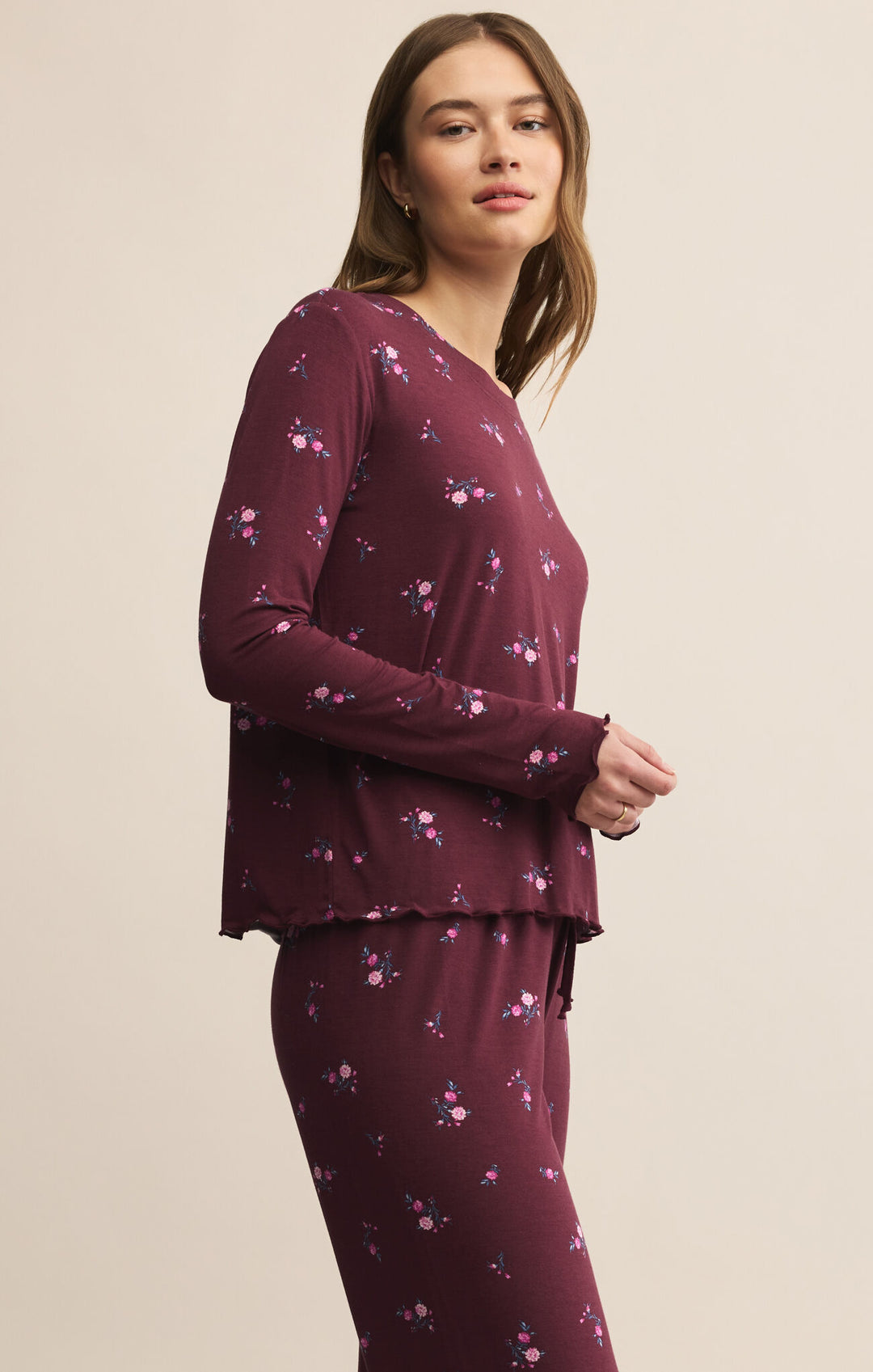 Woman wearing a burgundy long-sleeve top and pants with a subtle pattern on a beige background