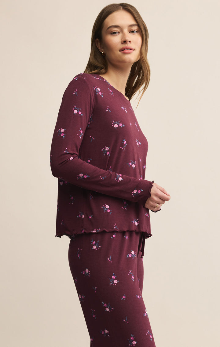 Woman wearing a burgundy long-sleeve top and pants with a subtle pattern on a beige background