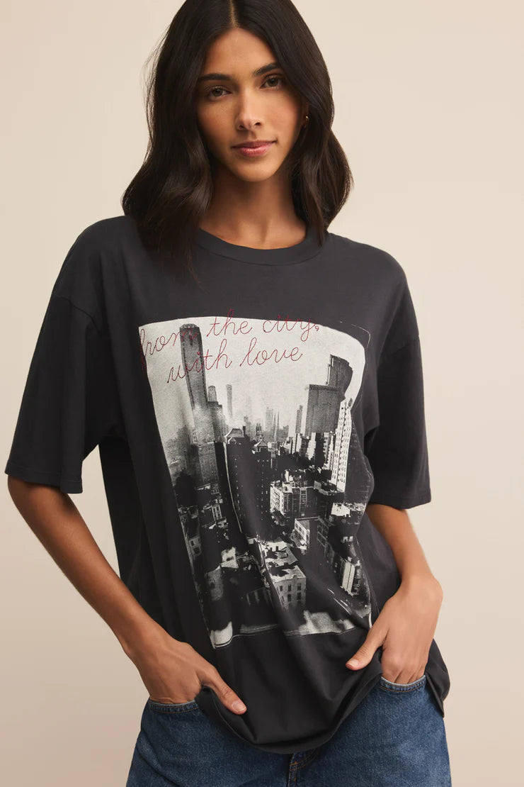 Woman wearing a black t-shirt with a cityscape graphic and text.