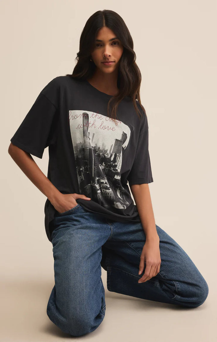 Woman wearing a black t-shirt with graphic design and blue jeans on a beige background