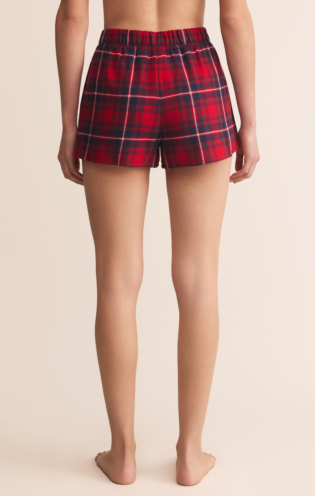 Red plaid shorts worn by a person on a beige background