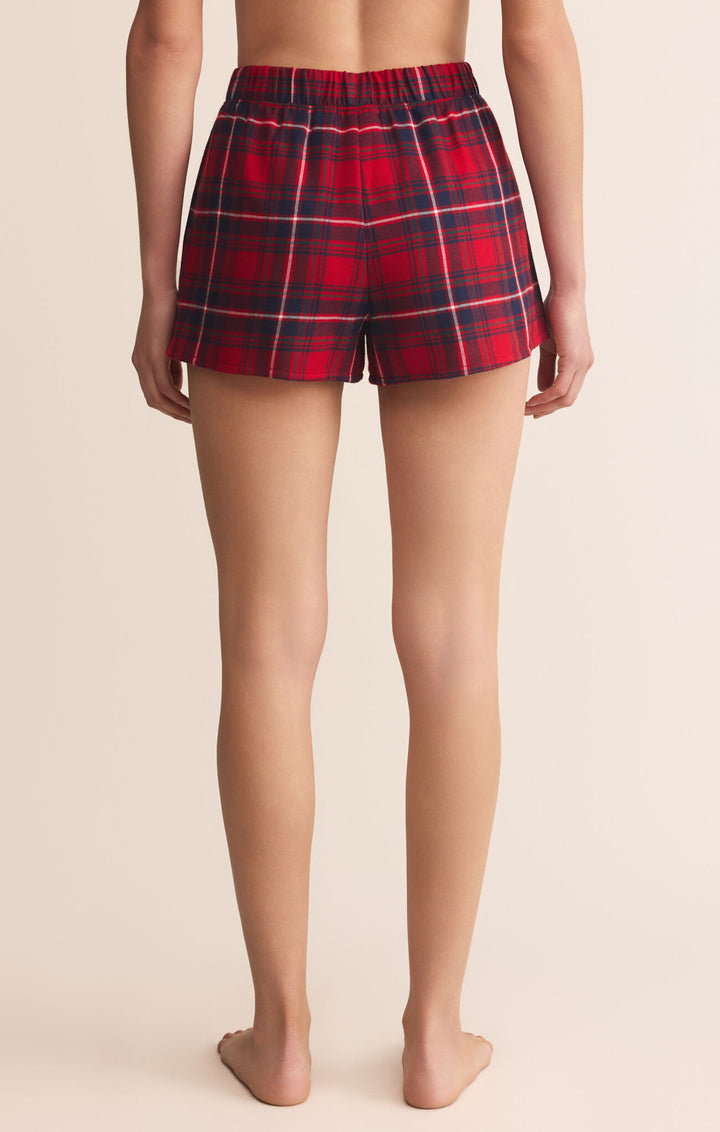 Red plaid shorts worn by a person on a beige background