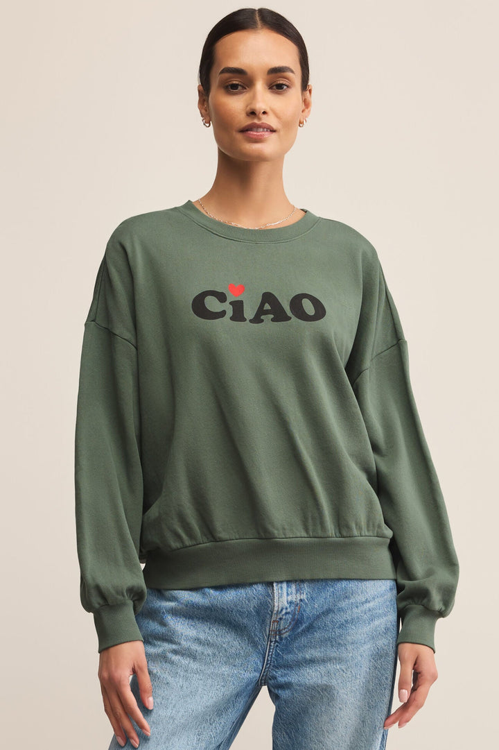 Person wearing a green sweatshirt with 'CIAO' text and a heart symbol on a beige background