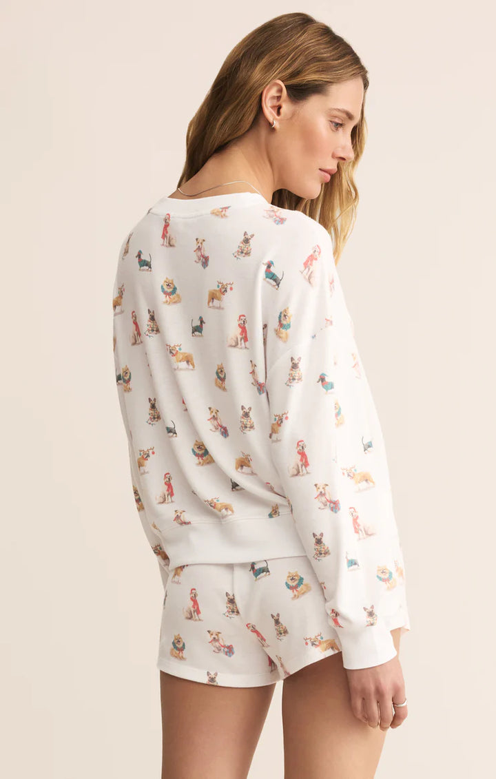 Woman wearing a Z Supply white pajama set with dogs in winter clothing pattern