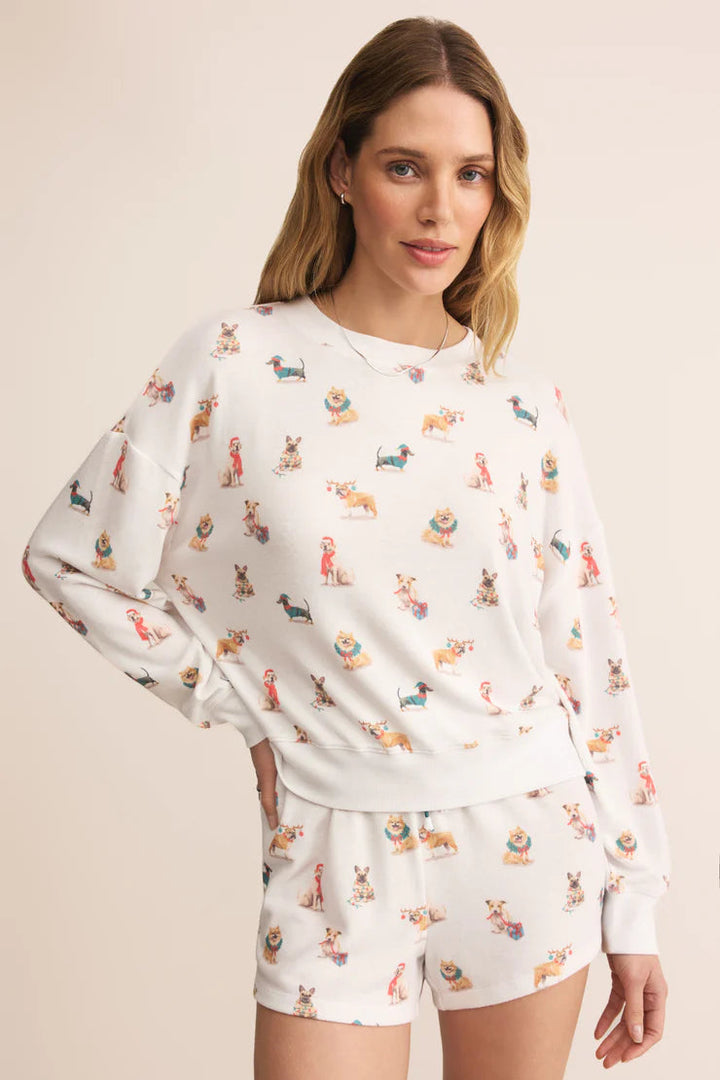Woman wearing a Z Supply long sleeve white pajama set with dogs in winter clothing pattern