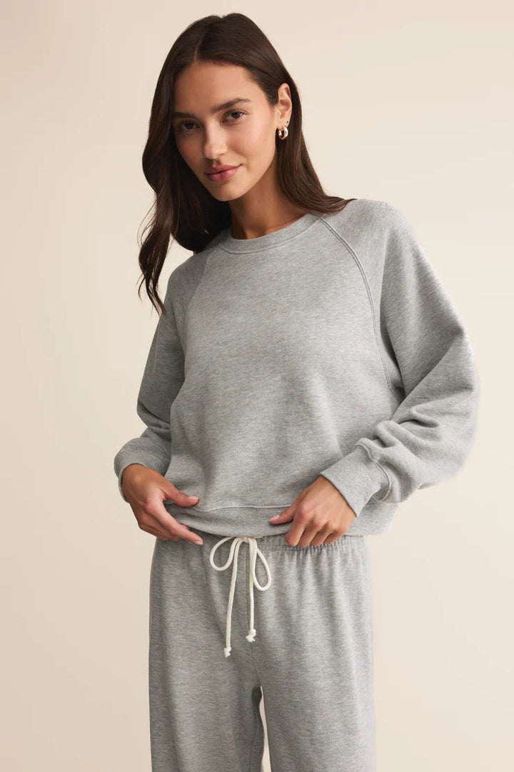 Woman wearing a gray sweatshirt and pants set on a beige background