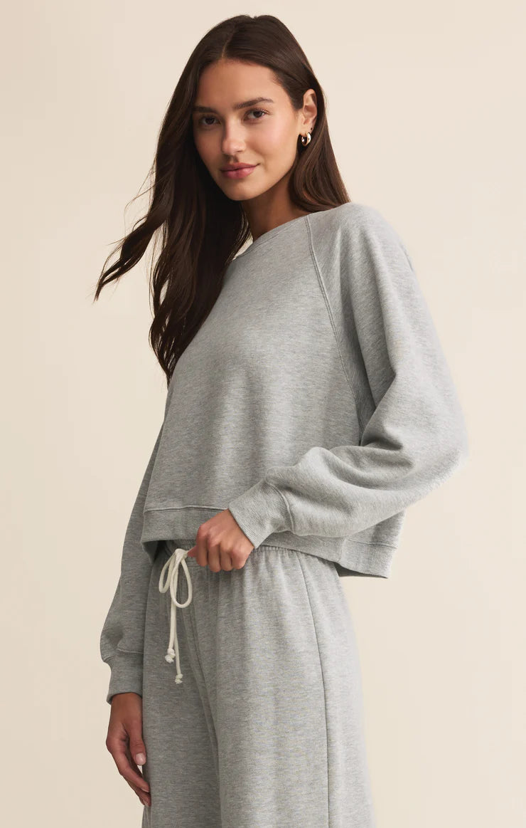Woman wearing a gray sweatshirt and pants on a beige background