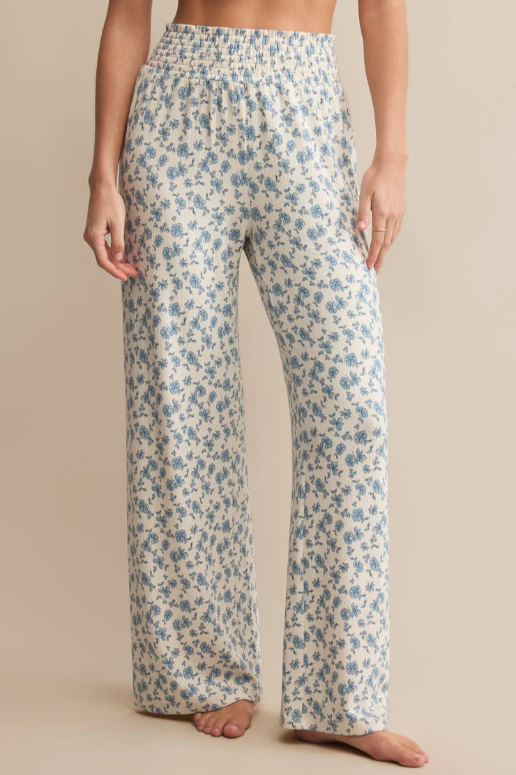 Floral patterned lounge pants pants cream colored with blue pattern worn by a person on a beige background
