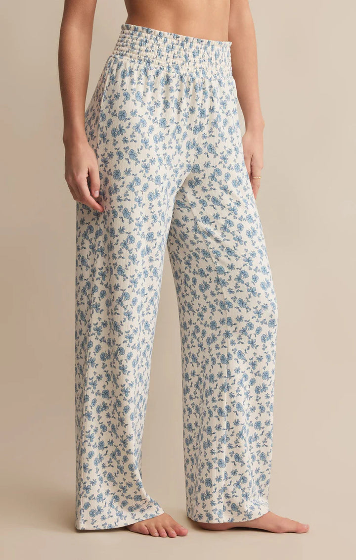 cream and blue floral-patterned lounge pants worn by a person on a beige background
