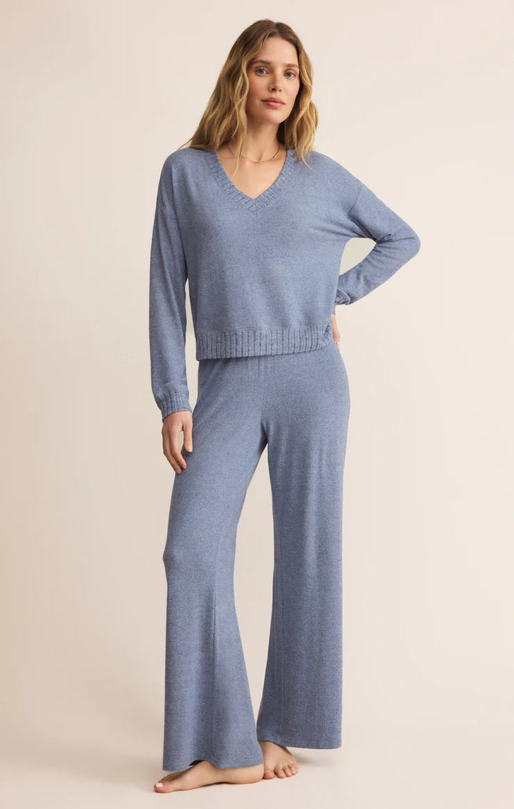 Woman wearing a blue knit sweater and matching pants on a beige background