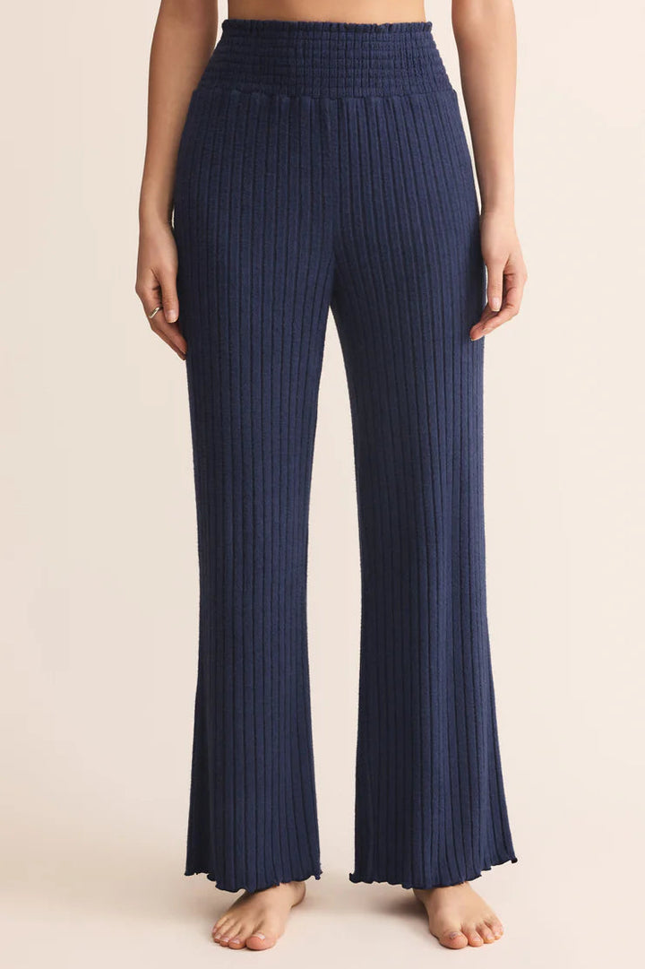 Navy ribbed pants worn by a person on a beige background