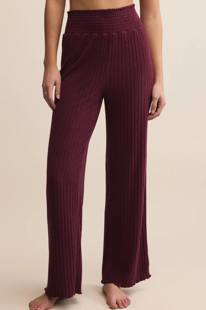 Maroon ribbed lounge pants worn by a person on a beige background