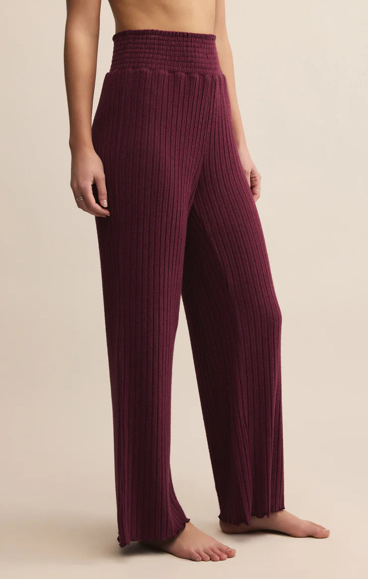 Maroon ribbed lounge pants worn by a person on a beige background