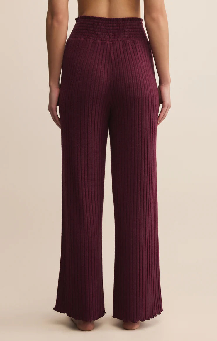 Maroon ribbed lounge pants worn by a person on a beige background