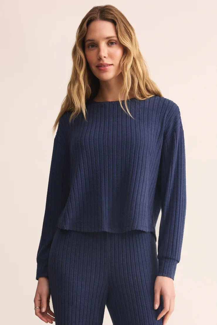 Woman wearing a blue ribbed cropped sweater on a beige background