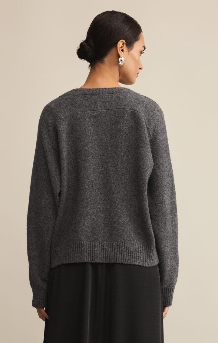 Person wearing a gray sweater against a beige background