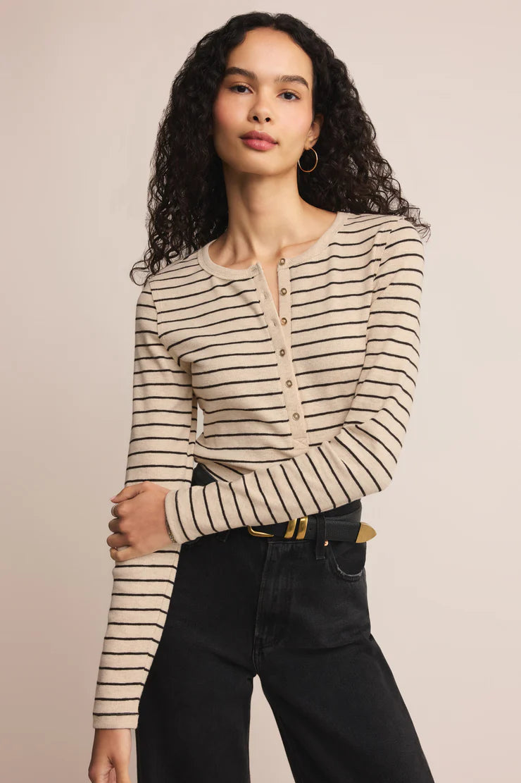 Woman wearing a striped long-sleeve Henry half button top with a plain background