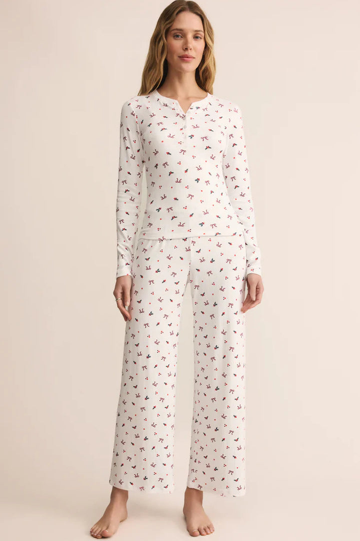 Woman wearing a white Z Supply long-sleeve top with small holiday pattern of bows and holly, half button