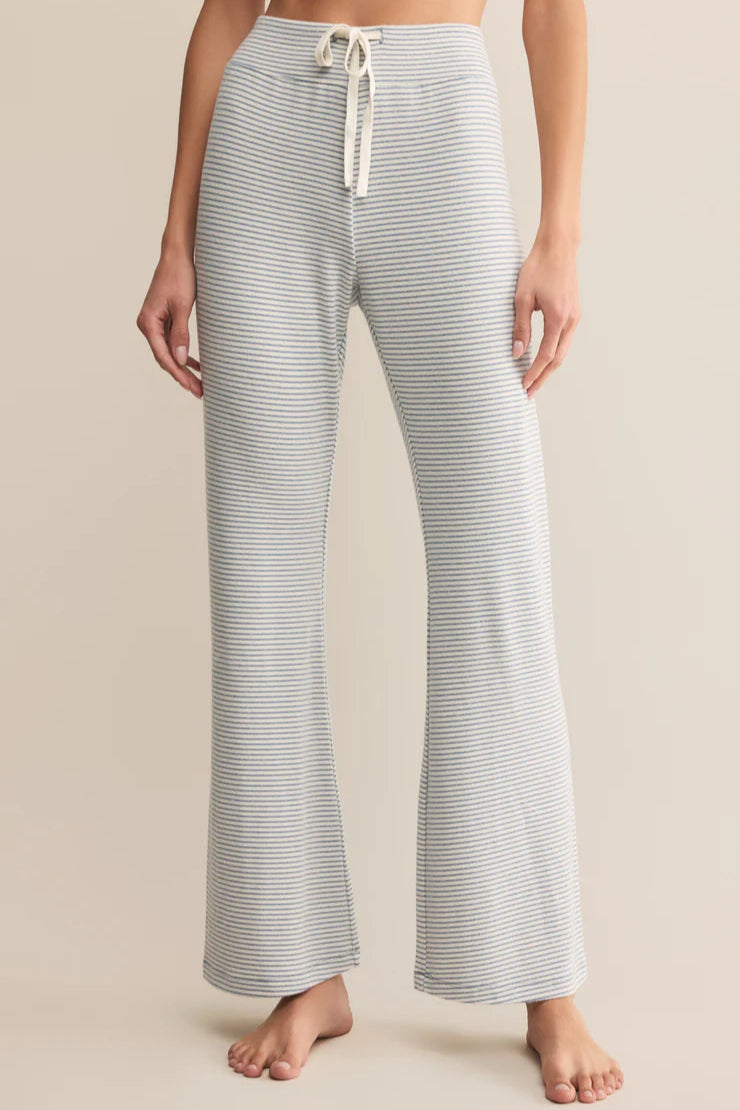 light blue striped lounge pants worn by a person on a beige background