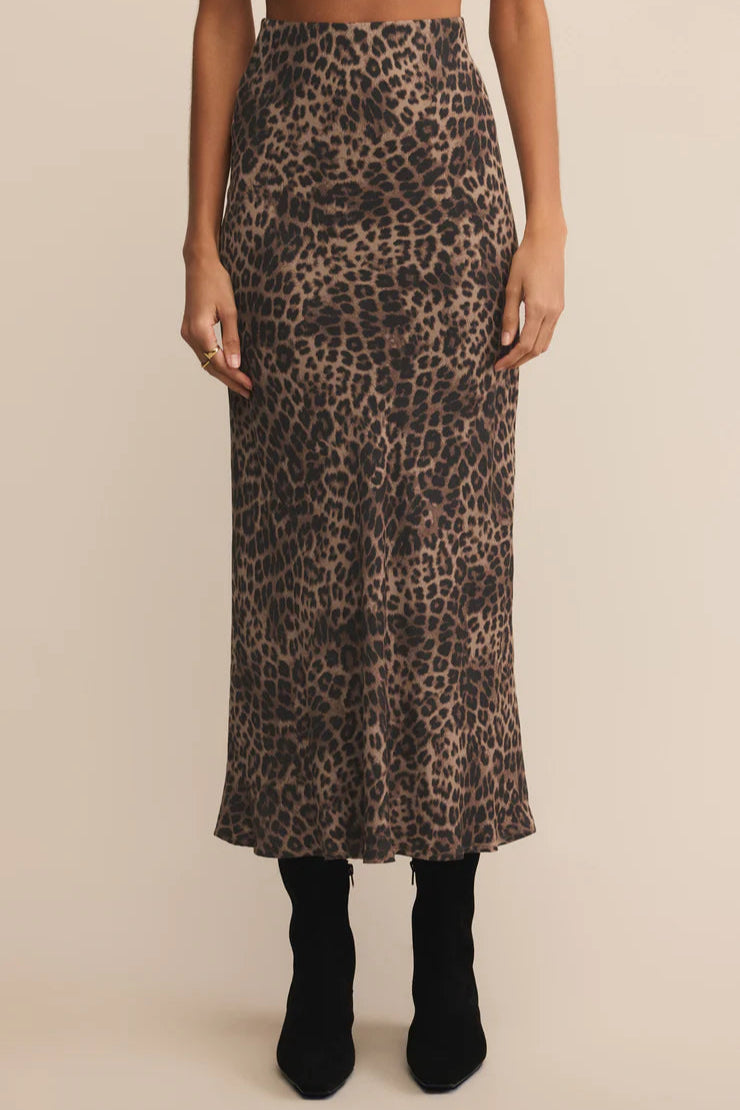 Person wearing a leopard print midi skirt on a beige background