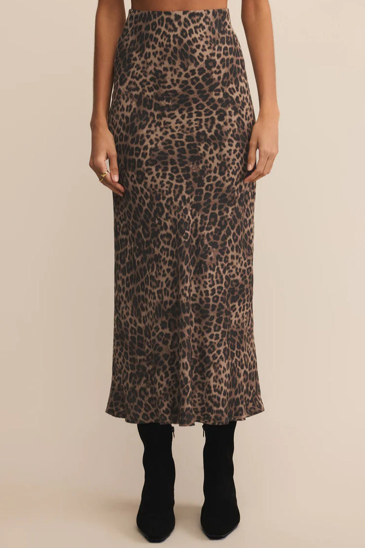 Person wearing a leopard print midi skirt on a beige background