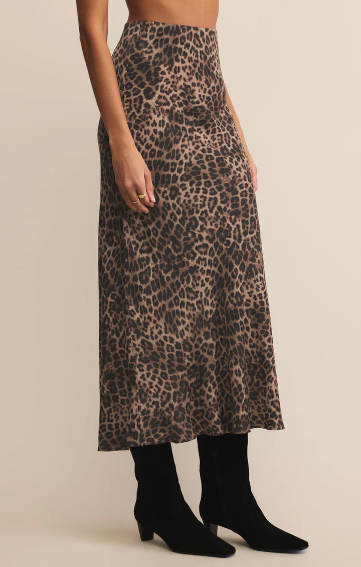 Person wearing a leopard print midi skirt on a beige background
