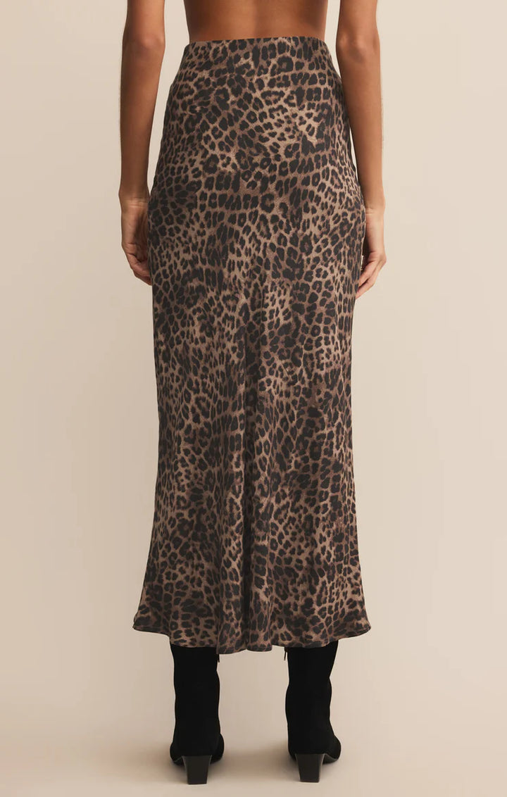 Person wearing a leopard print midi skirt on a beige background