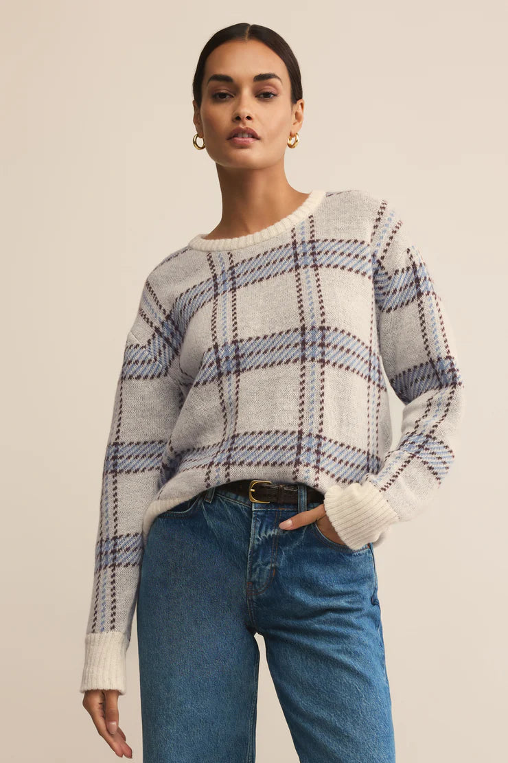 Woman wearing a plaid sweater and blue jeans on a beige background