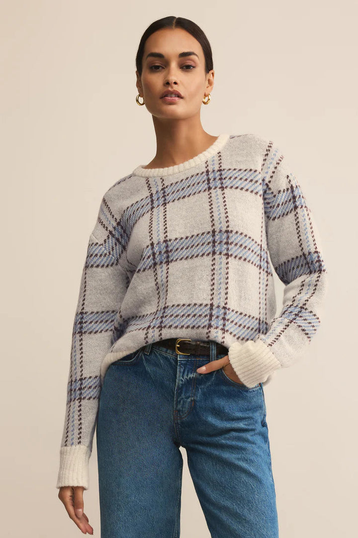 Woman wearing a plaid sweater and blue jeans on a beige background