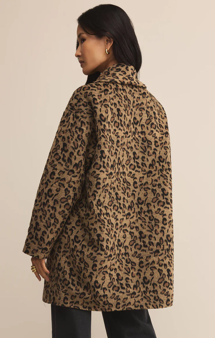 Person wearing a leopard print coat against a beige background