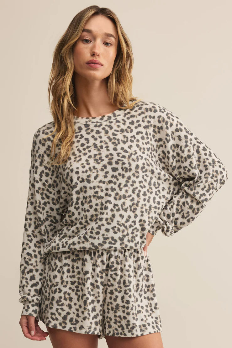 Woman wearing a leopard print matching lounge set on a beige background