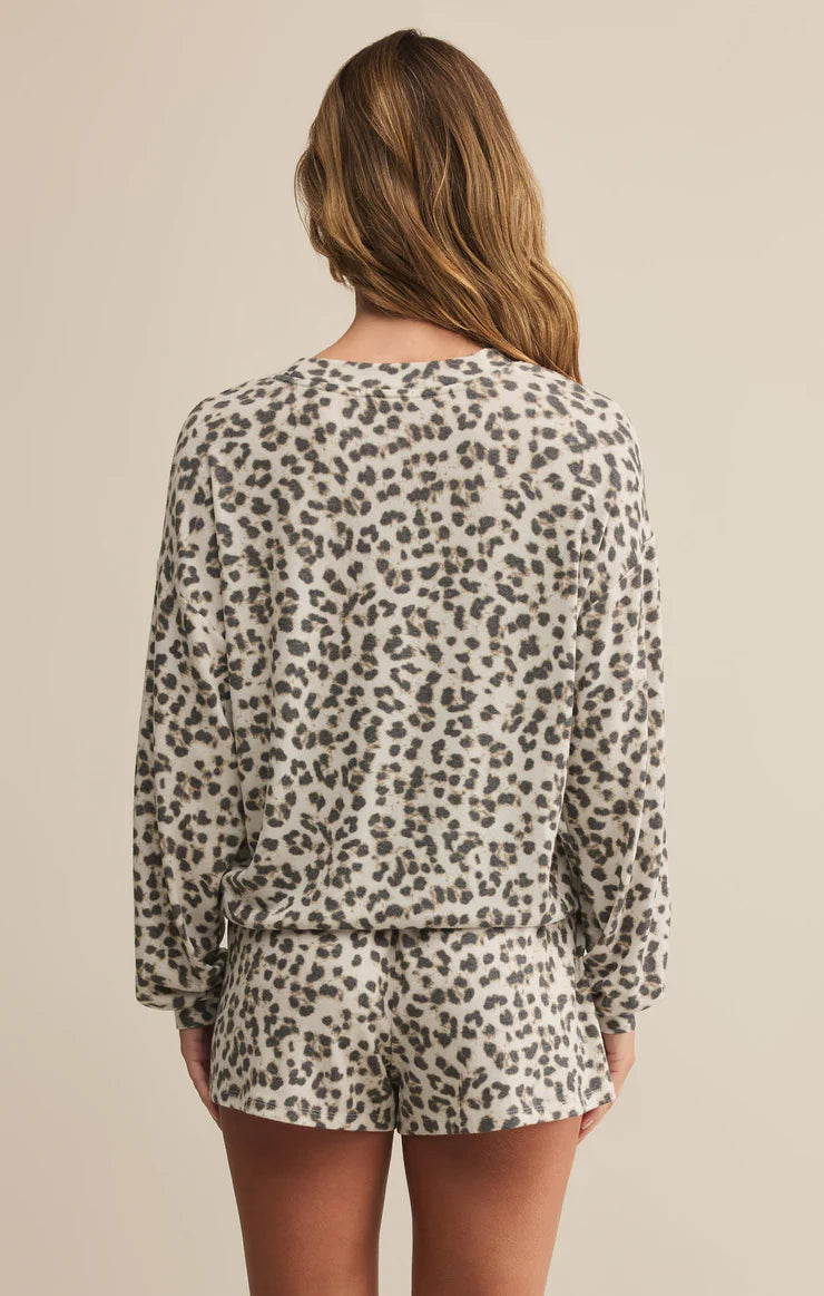 Person wearing a leopard print long-sleeve top and shorts set on a beige background