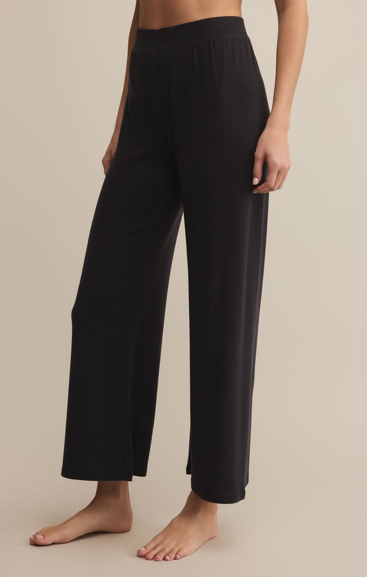 Black lounge pants worn by a person on a beige background