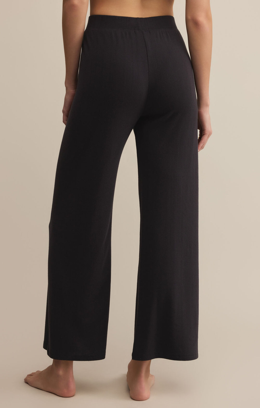 Black wide-leg pants worn by a person on a beige background