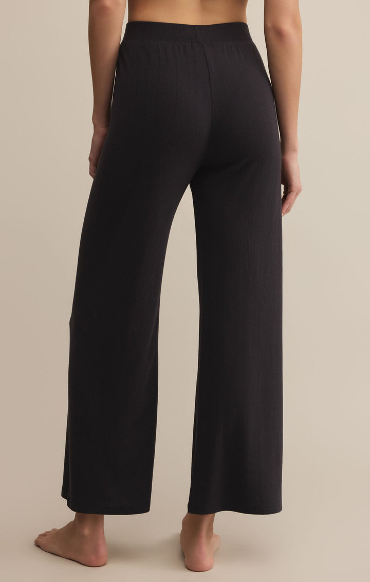 Black wide-leg pants worn by a person on a beige background