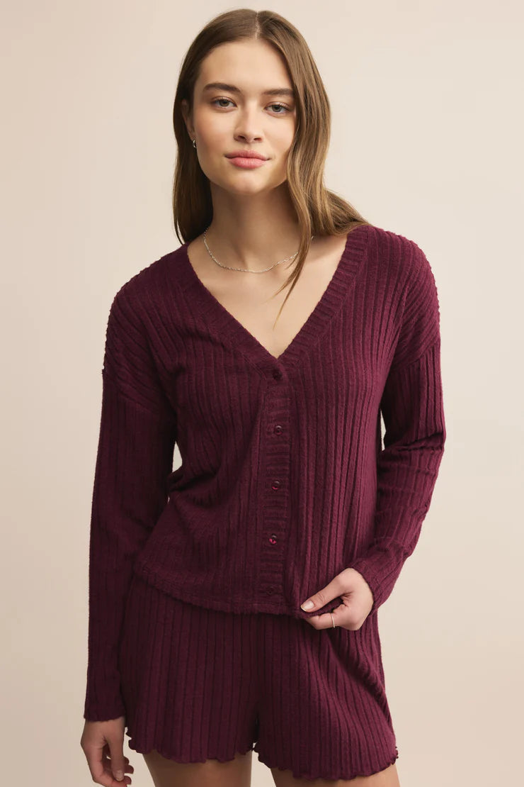 Woman wearing a ribbed marron button front cardigan and shorts set on a beige background