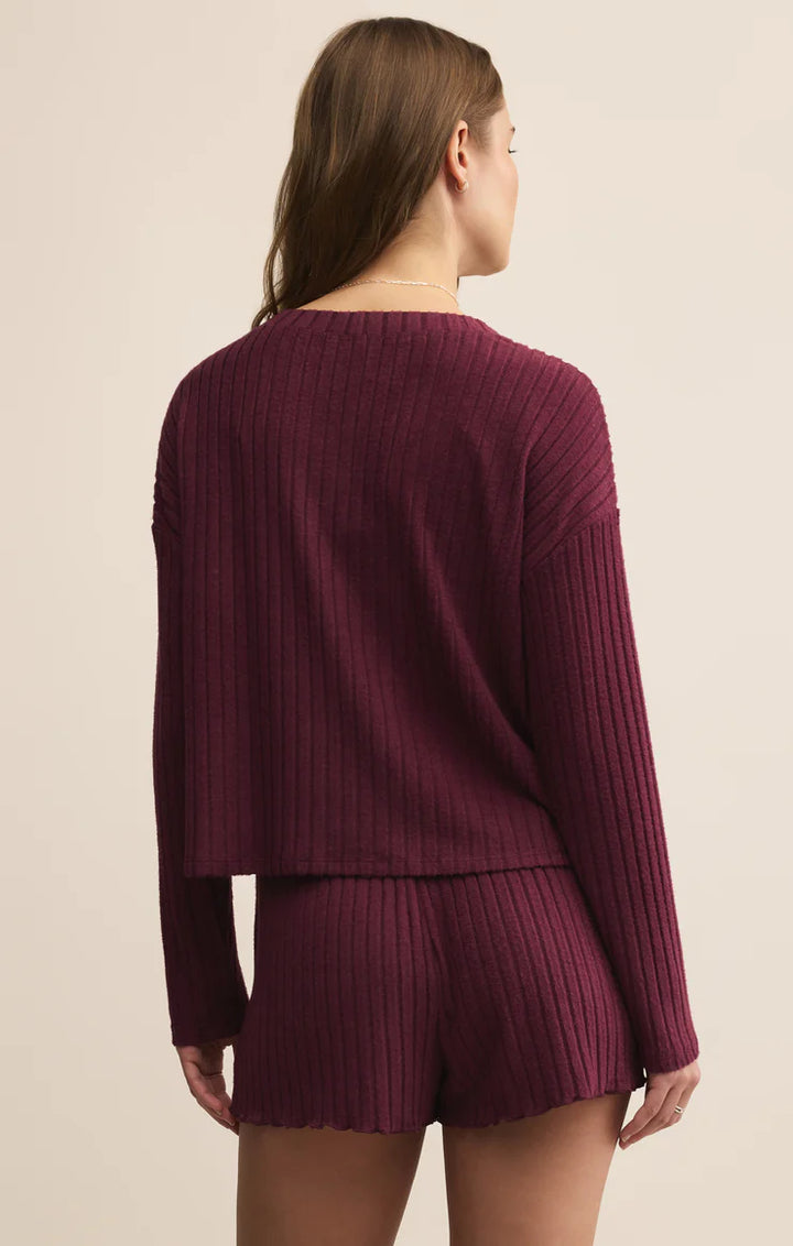 Woman wearing a maroon ribbed cardigan sweater and shorts set on a beige background
