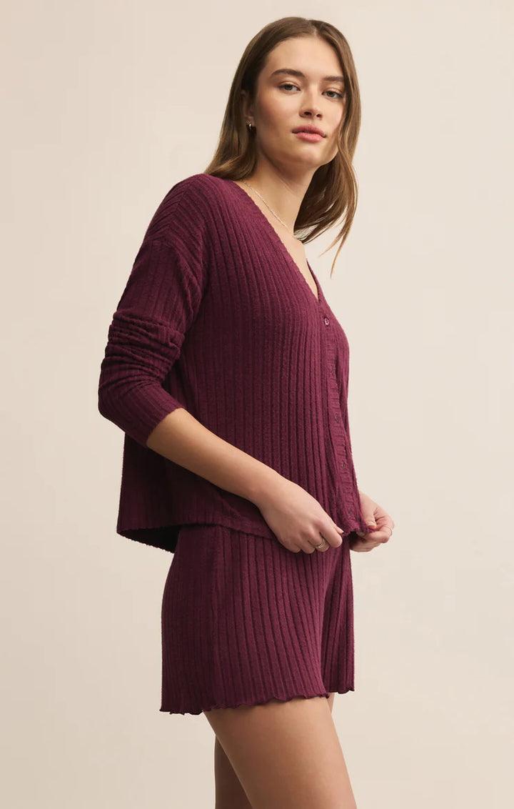 Woman wearing a ribbed maroon outfit set on a beige background