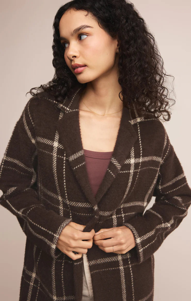 Woman wearing a brown plaid coat against a neutral background