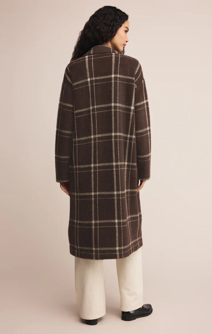 Person wearing a brown plaid coat on a beige background