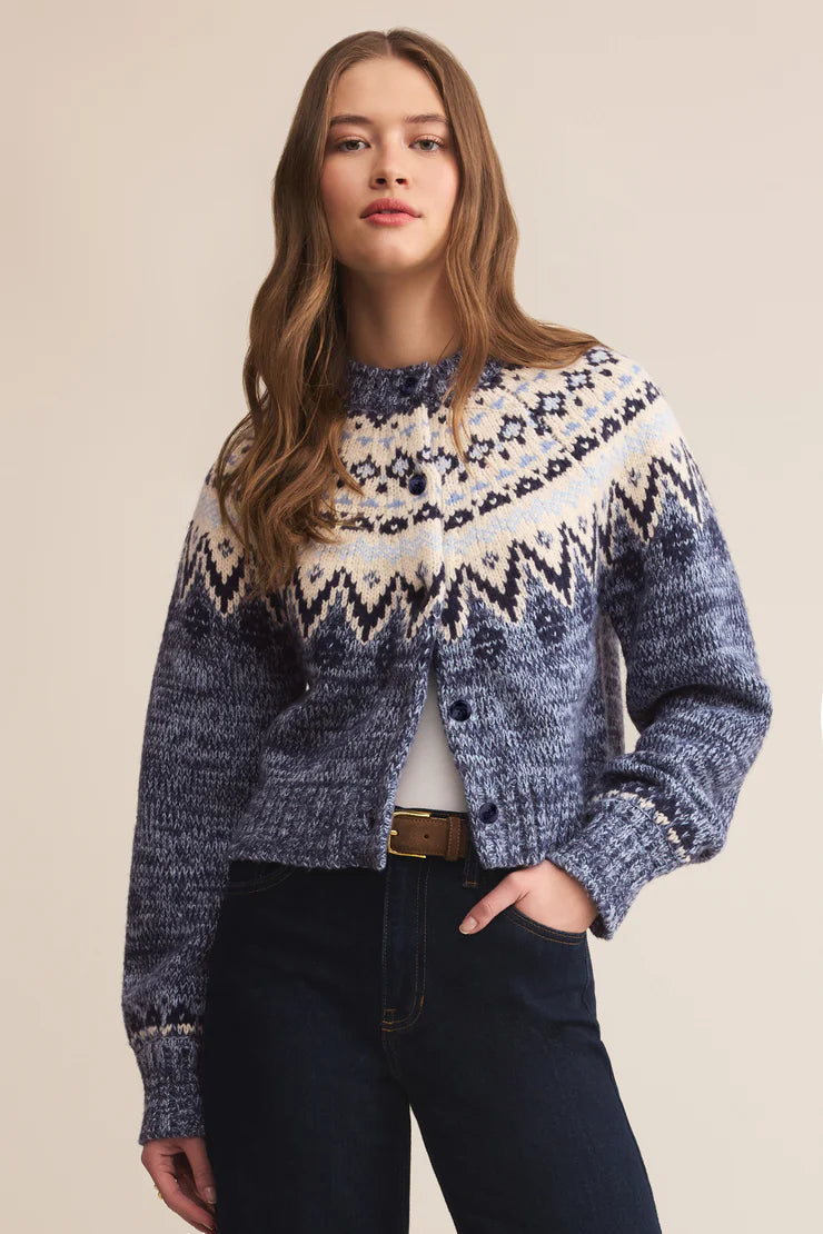 Woman wearing a blue and white patterned cardigan against a beige background