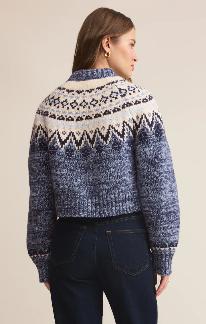 Woman wearing a blue and white patterned cardigan  against a beige background