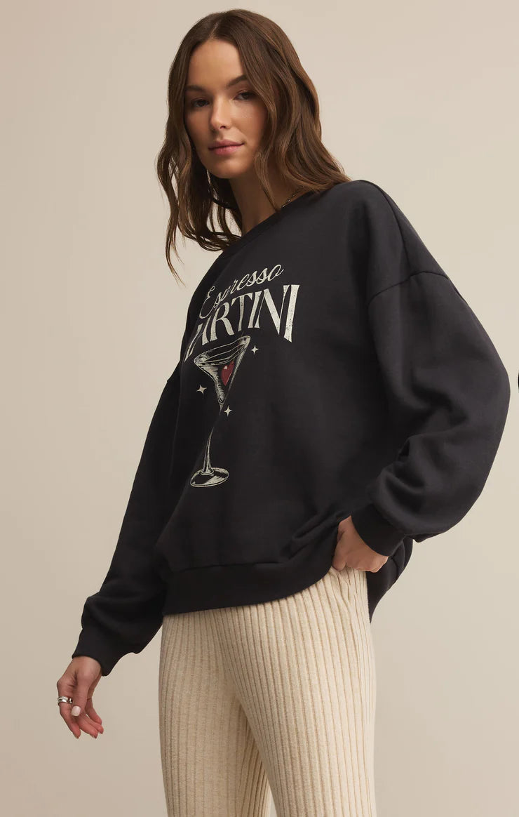Woman wearing a black sweatshirt with 'Espresso Martini' design on a beige background