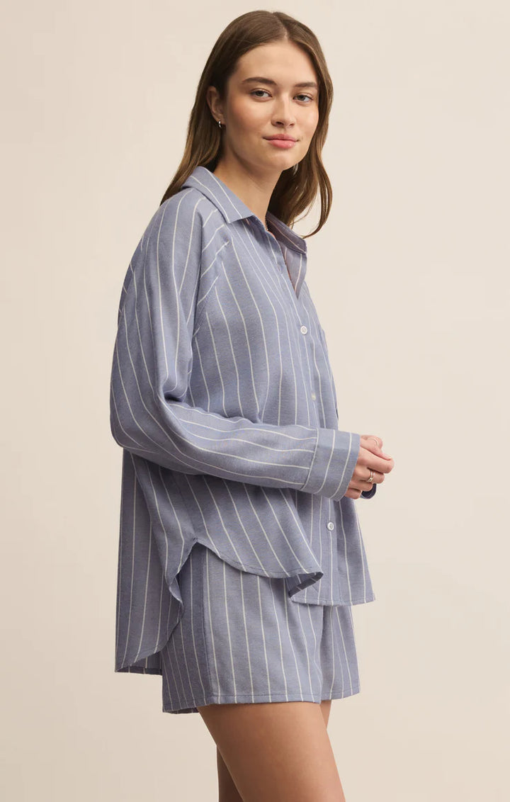Woman wearing a blue pinstripe shirt and shorts set on a beige background
