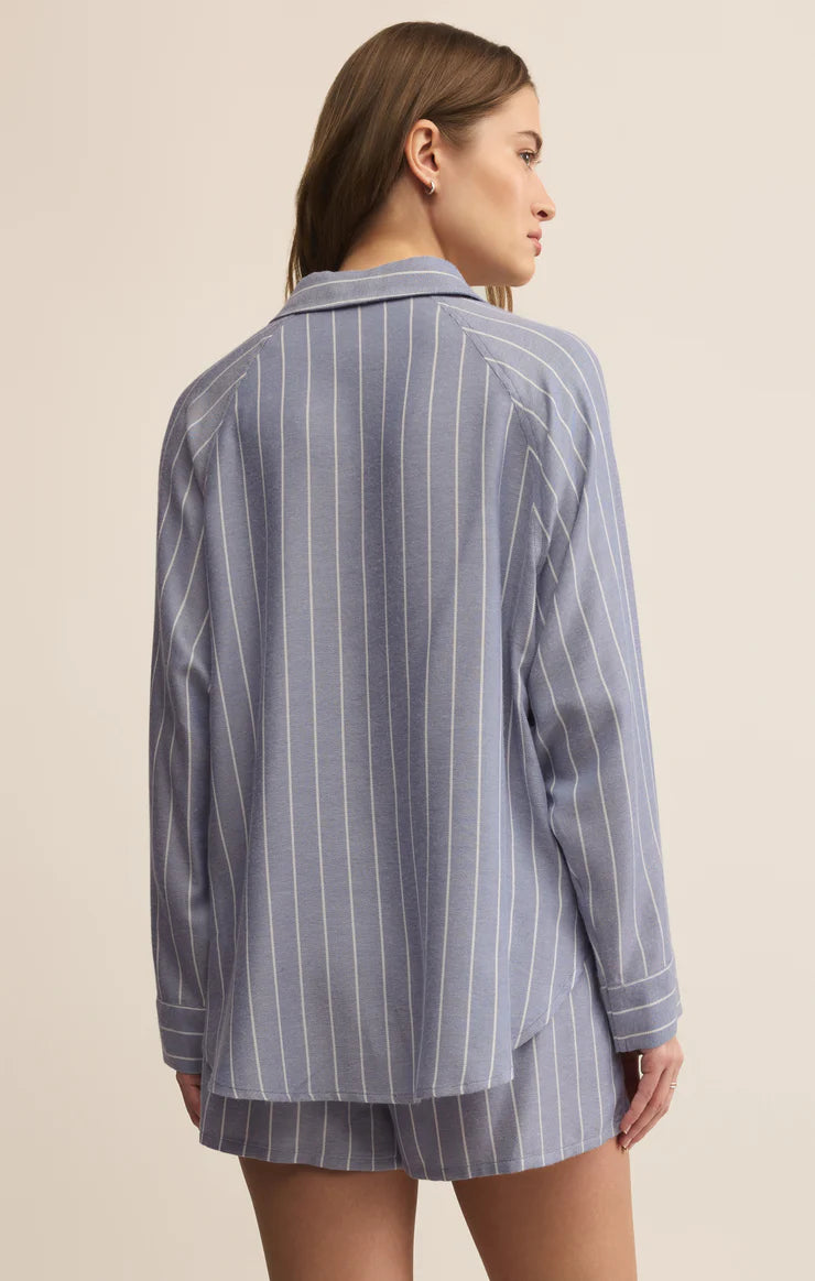 Woman wearing a blue pinstripe pajama set on a beige background