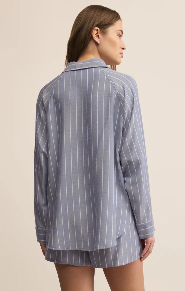 Woman wearing a blue pinstripe pajama set on a beige background