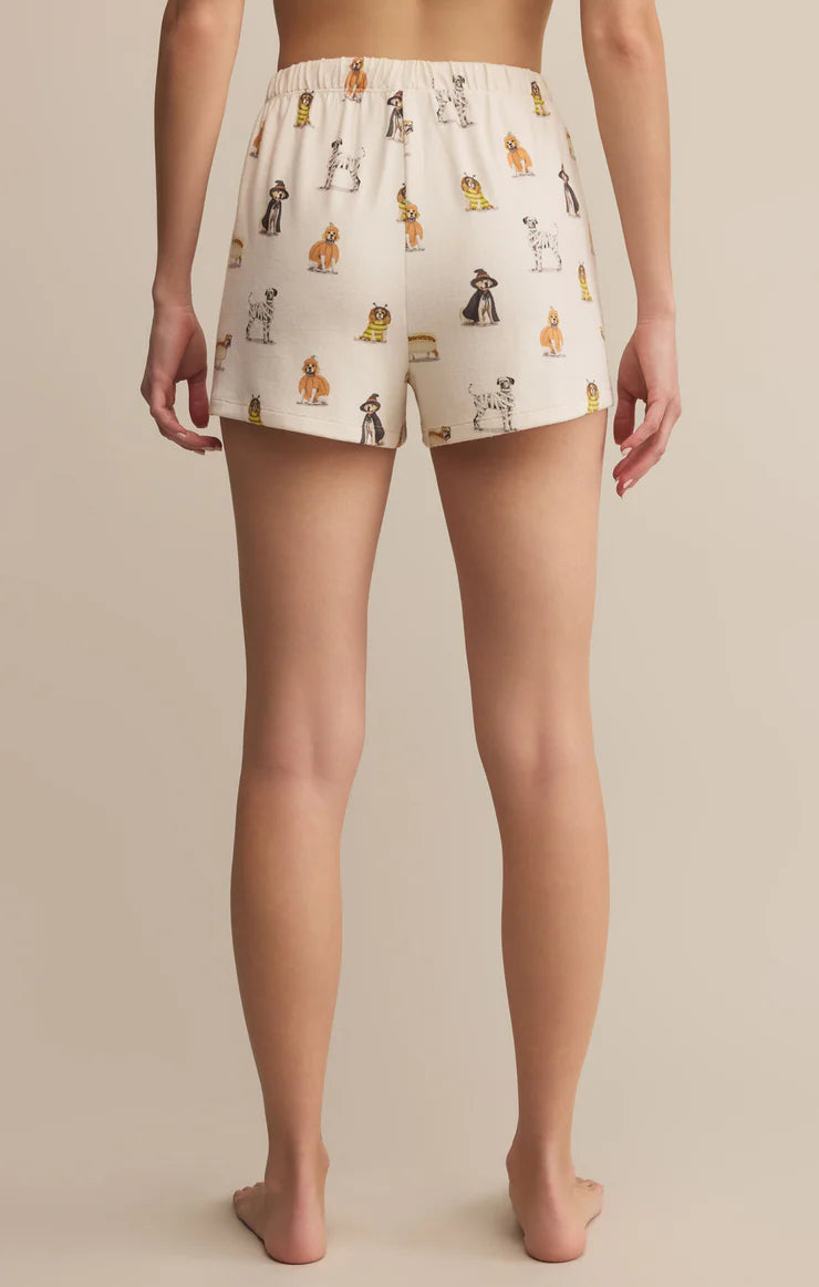 Person wearing cream-colored shorts with dog pattern on a beige background