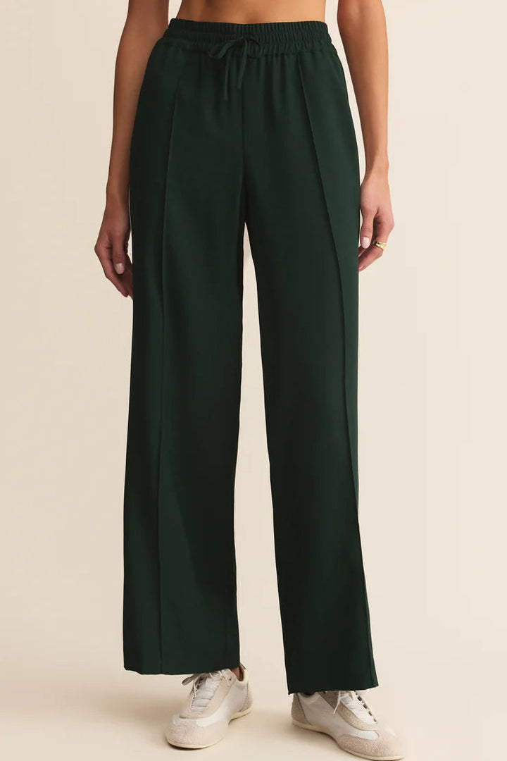 Dark green wide-leg pants worn by a person on a beige background