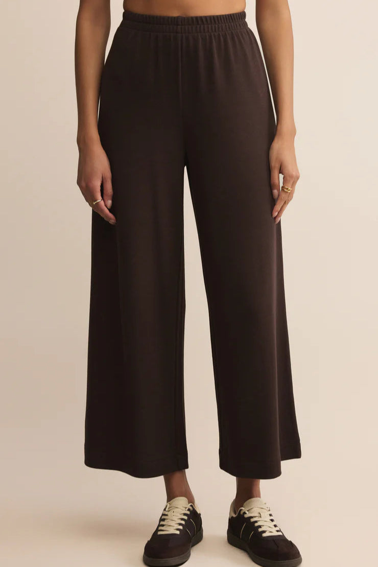 Person wearing black wide-leg pants on a beige background