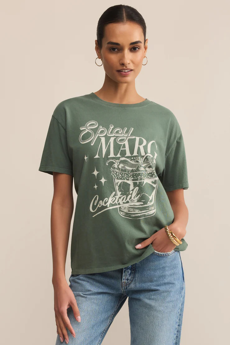 Woman wearing a green t-shirt with 'Spicy Martini Cocktail' text and graphic, standing against a beige background.